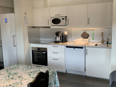 Modern apartment kitchen with white cabinets and appliances.