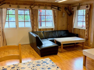 Living room with sofa, tables, and windows.