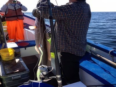 Fisherman with ling fish on motorboat.