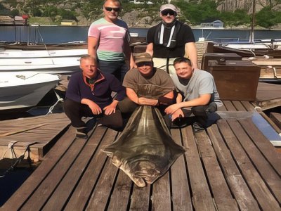 Guests posing with large halibut on dock.