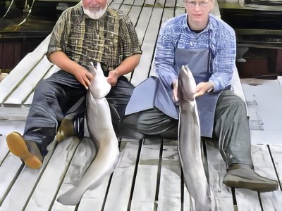 Two guests with large ling fish seated on dock.