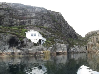 White seaside house at the base of cliffs in Sotra.